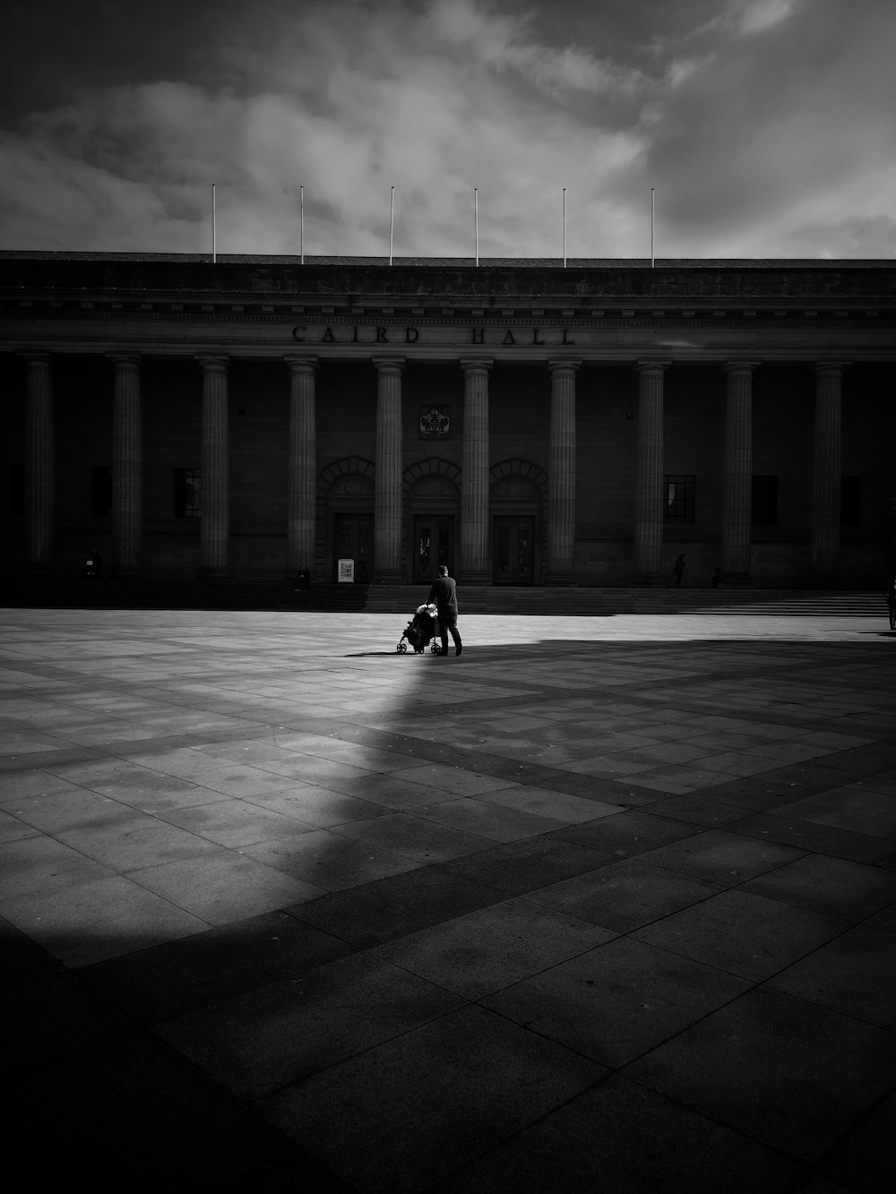 grayscale photography of person pushing stroller