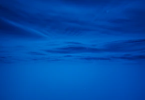 A sleek dark underwater scene showing a blue-lit subsea ROV gently exploring the ocean floor.