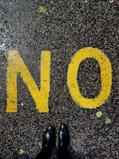 Close-up of a hand writing the word ‘No’ in bold letters on a notepad.
