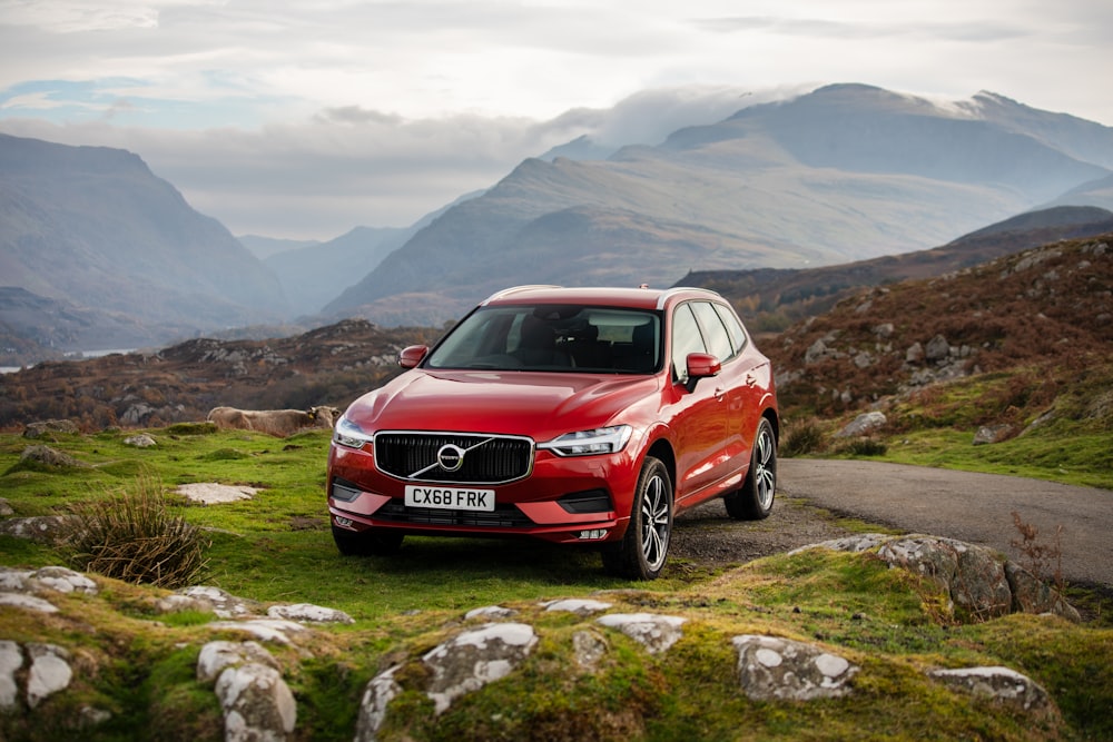 red Volvo SUV parking on green field