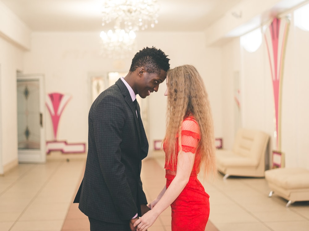 woman in red dress beside and man in black suit jacket