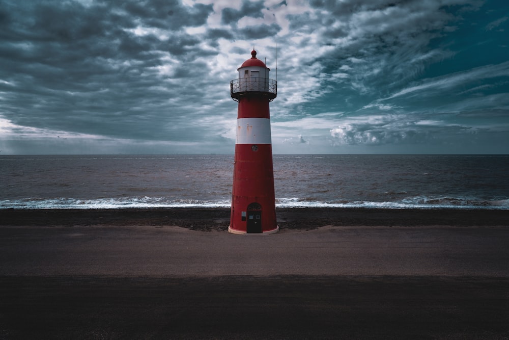 red and white lighthouse under gray clouds at dyatime