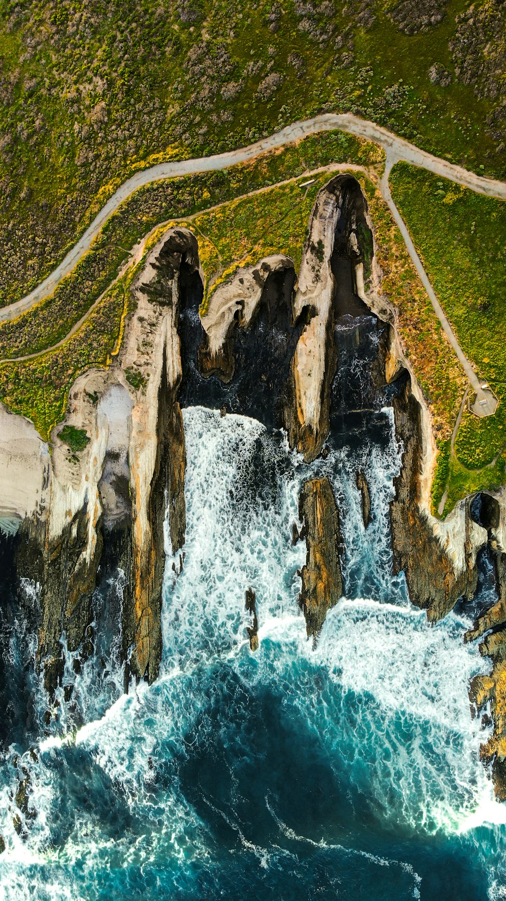 waves breaking on brown rock cliff in beach