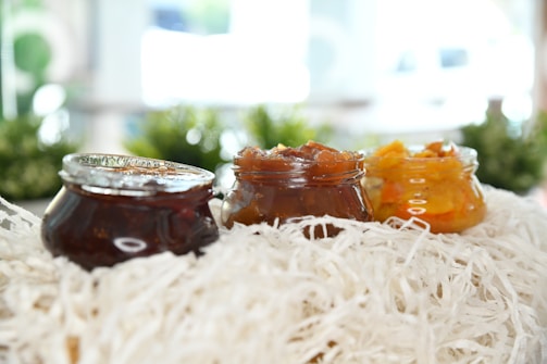 Close-up of vibrant fruit jams in glass jars with rustic wooden background.