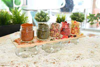 Elegant glass jars filled with colorful spices arranged on a wooden table.
