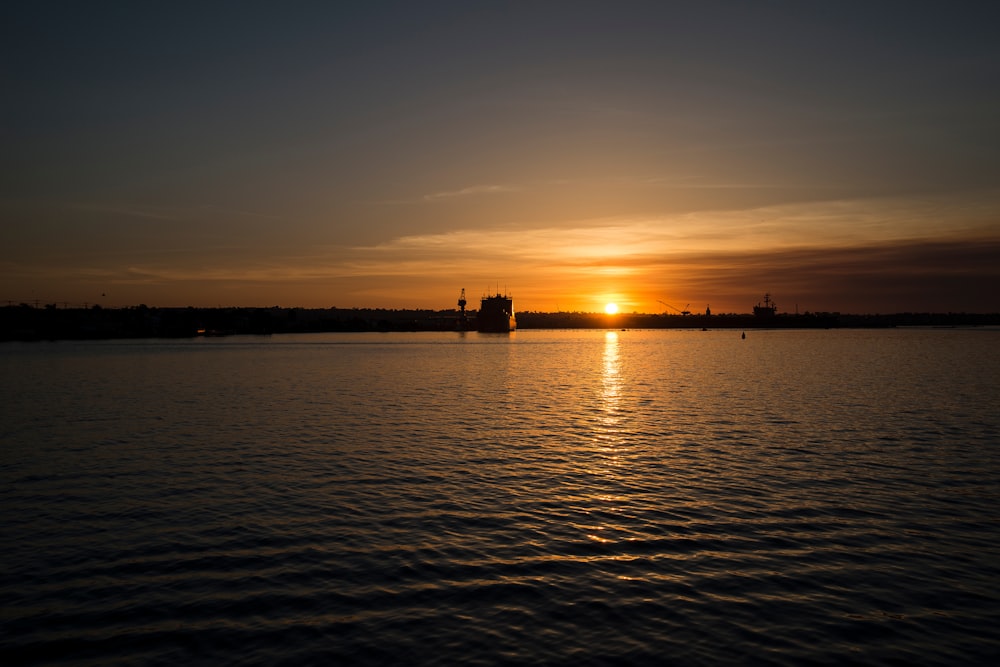 body of water near boat at golden hour