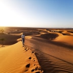 person walking on sand dunes