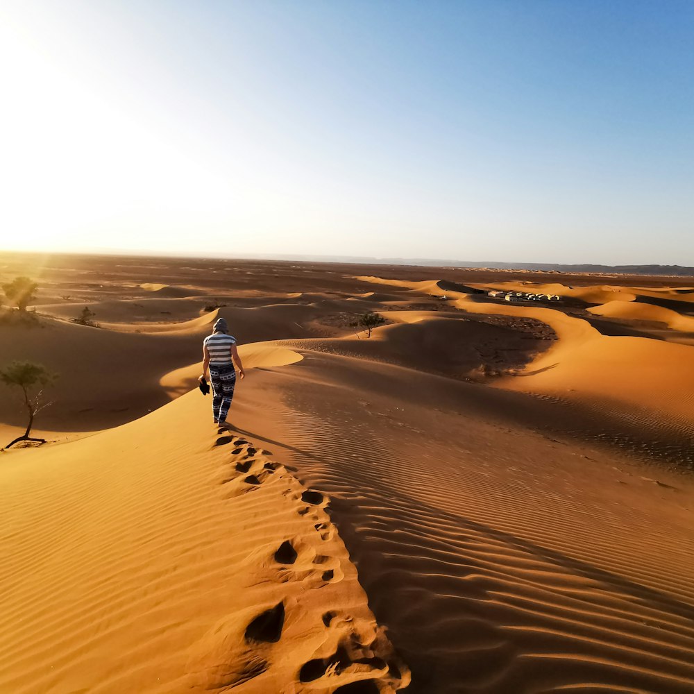 person walking on sand dunes