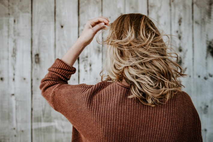 woman running fingers through hair showing early signs of hair shedding and thinning
