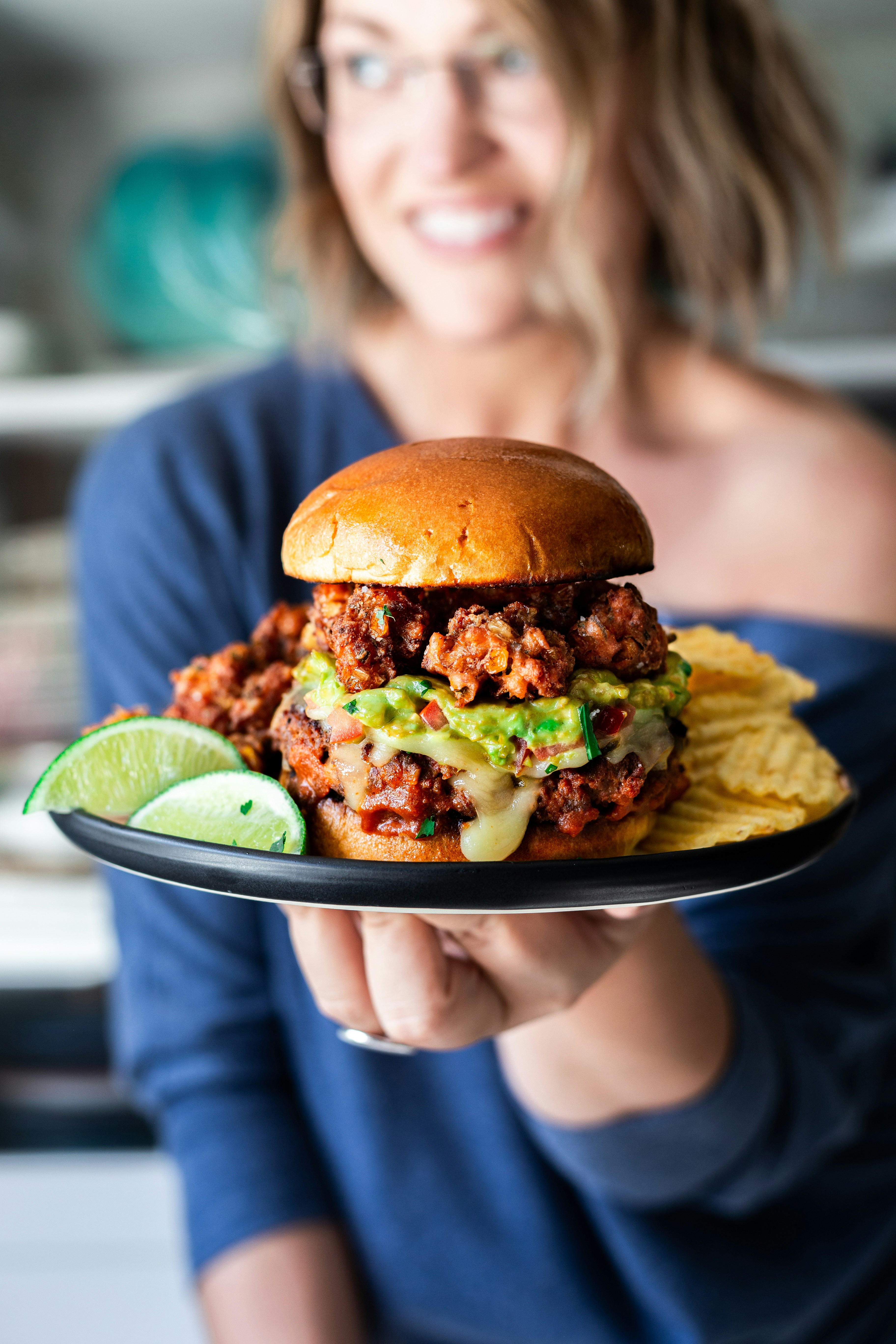 hamburger, chips and lime slices on a black plate