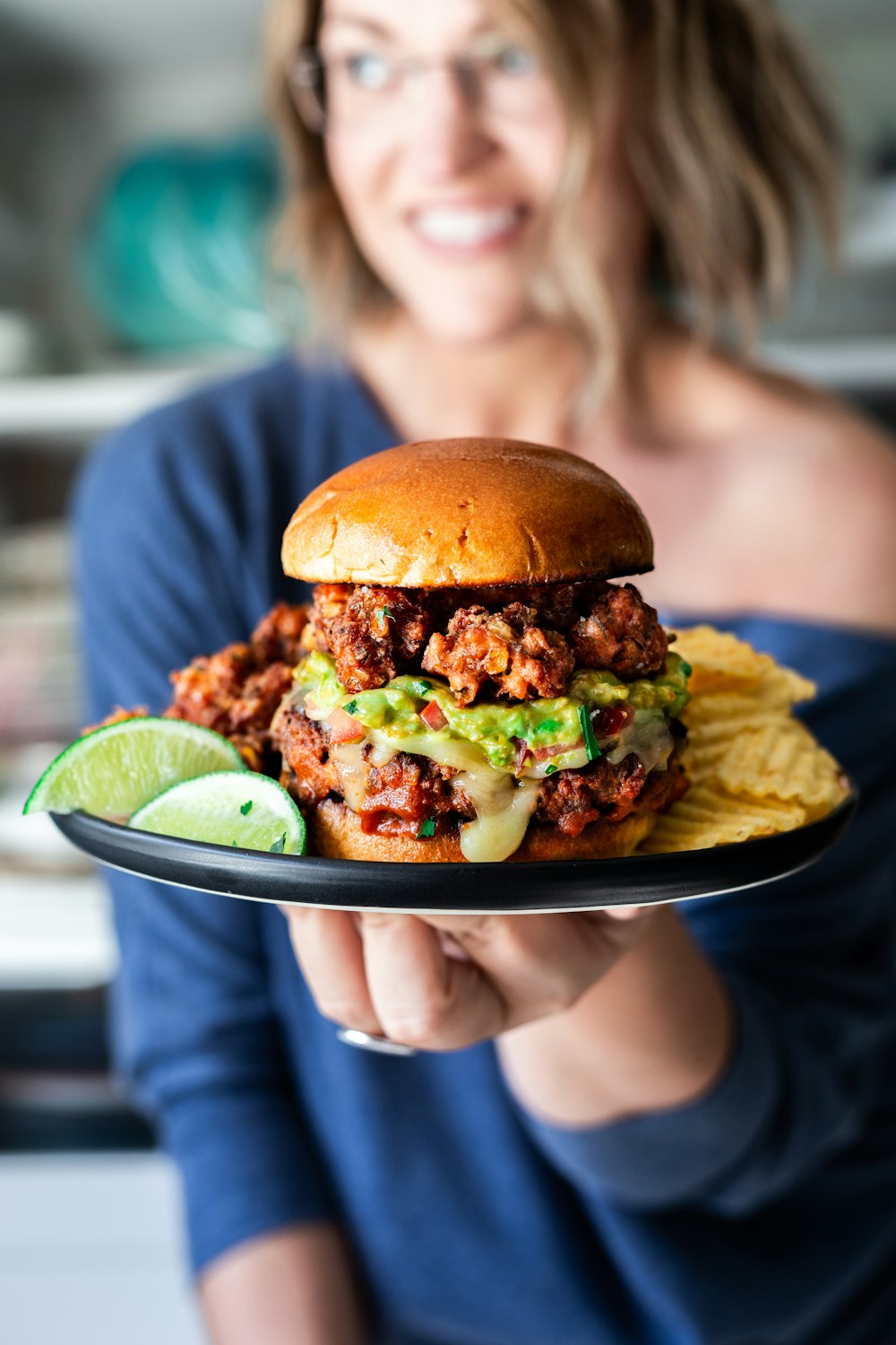 hamburger, chips and lime slices on a black plate