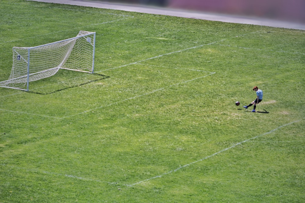 person kicking ball near white goalpost