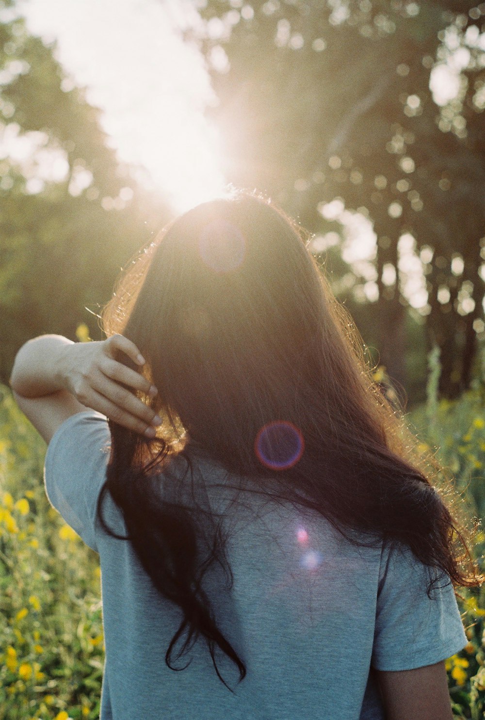 woman in white t-shirt walking on flower field during daytime