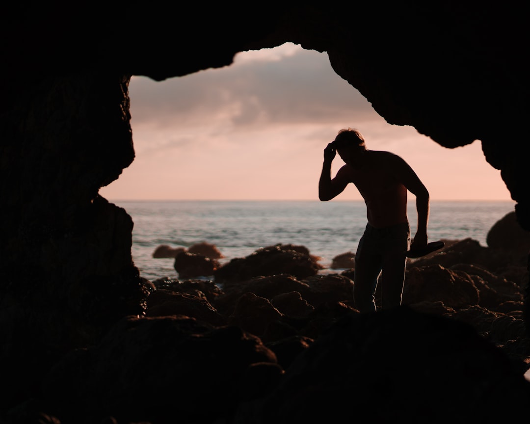 man in cave with ocean in background
