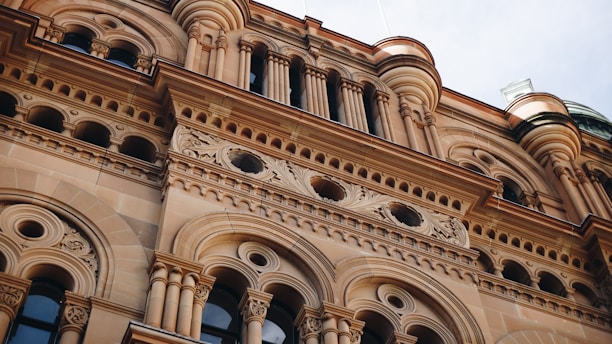 Architectural details of a classic building facade with ornate carvings, circular windows, and decorative columns, highlighting intricate stonework and craftsmanship.