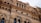 Architectural details of a classic building facade with ornate carvings, circular windows, and decorative columns, highlighting intricate stonework and craftsmanship.