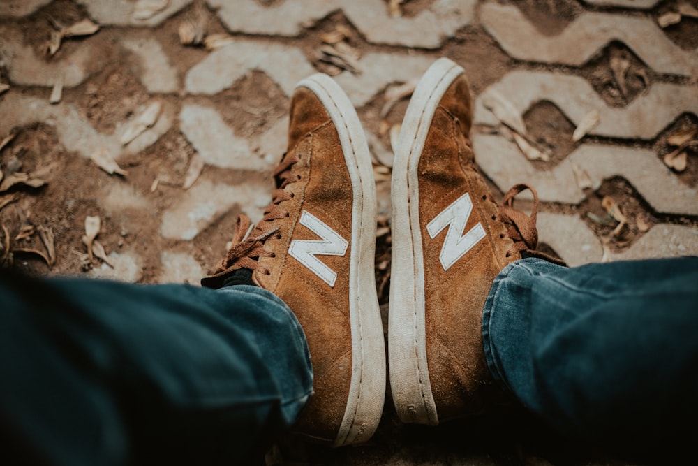 person in blue jeans and brown New Balance sneakers