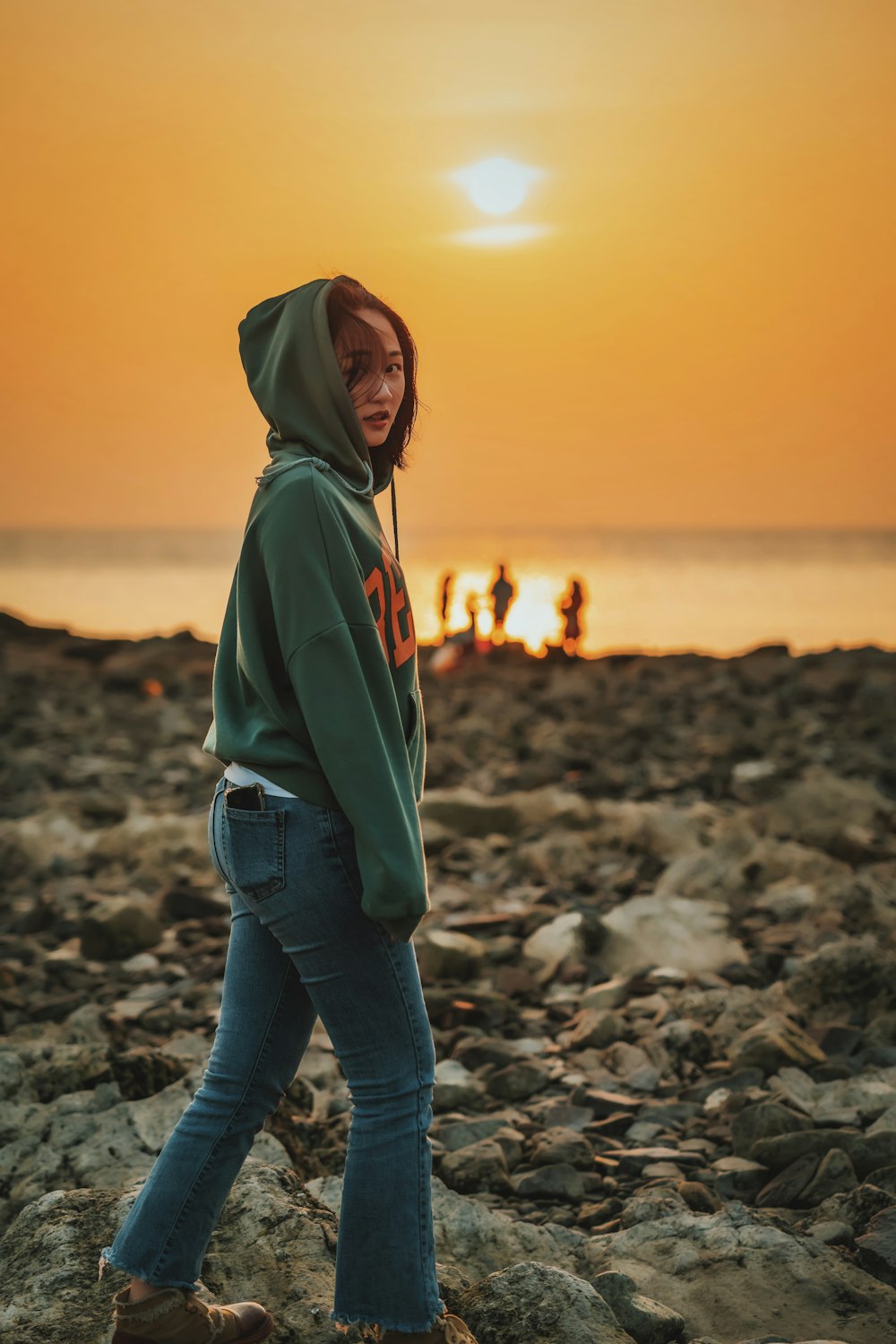 woman walking on rocky shore at sunset