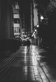 A silhouette of a well-dressed companion walking along a quiet London street under soft streetlights.