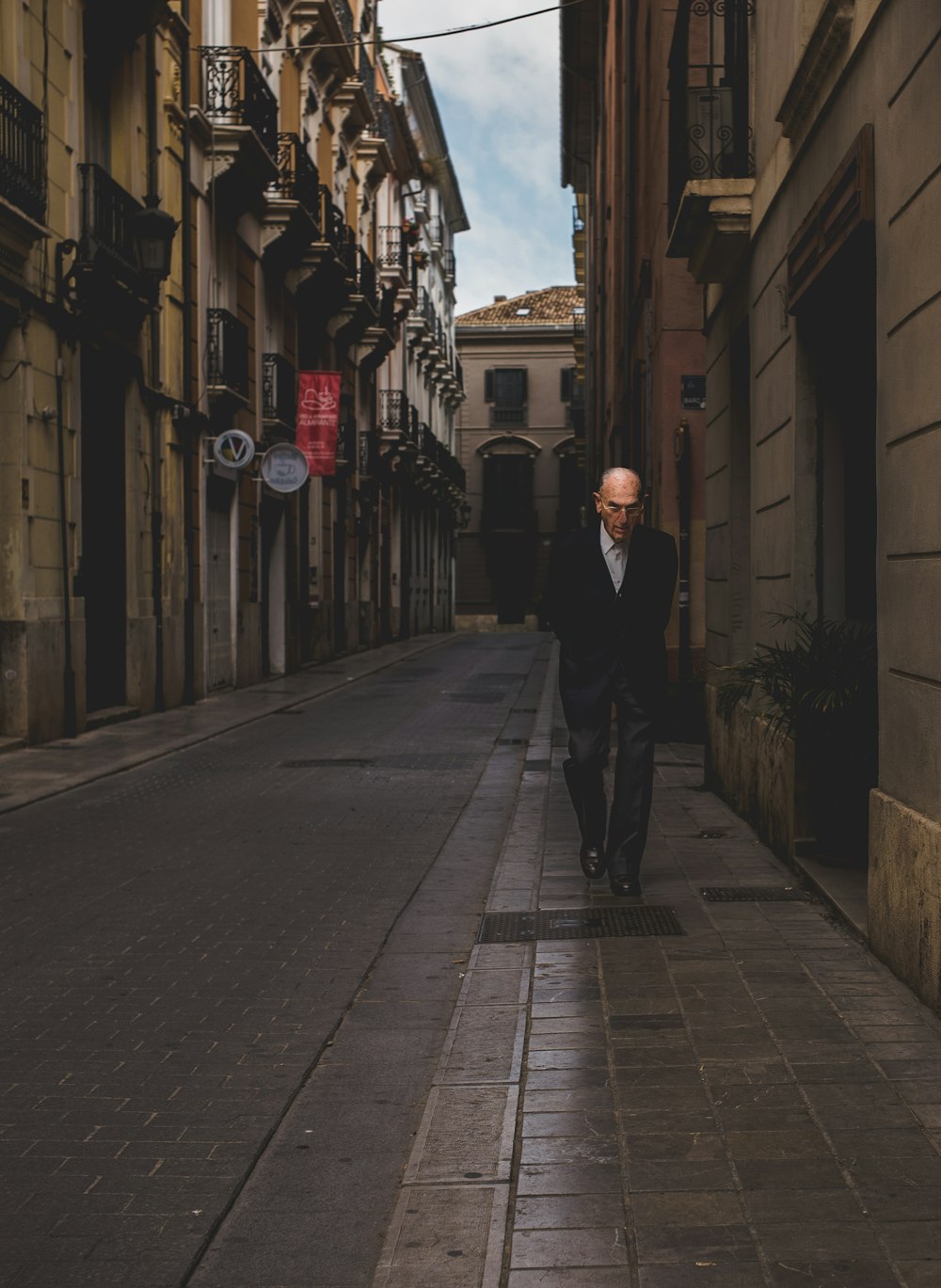 man walking alone near road beside buildings