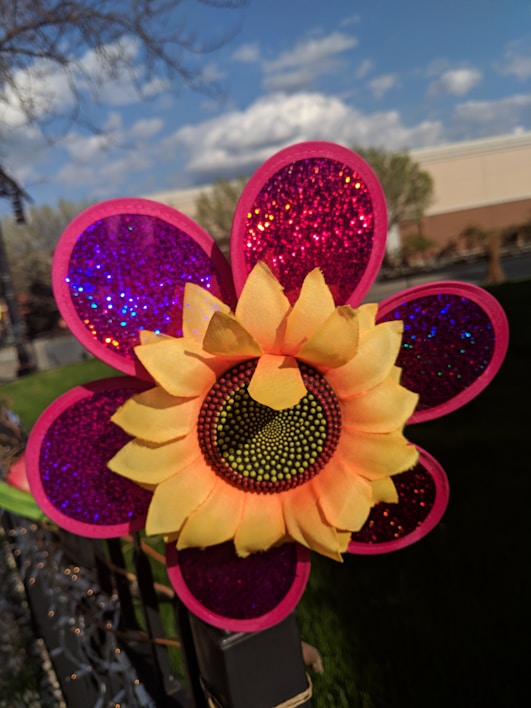 A colorful garden stake with floral designs shining under the sun.