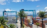 A busy port with containers being loaded onto a cargo ship under a clear blue sky.