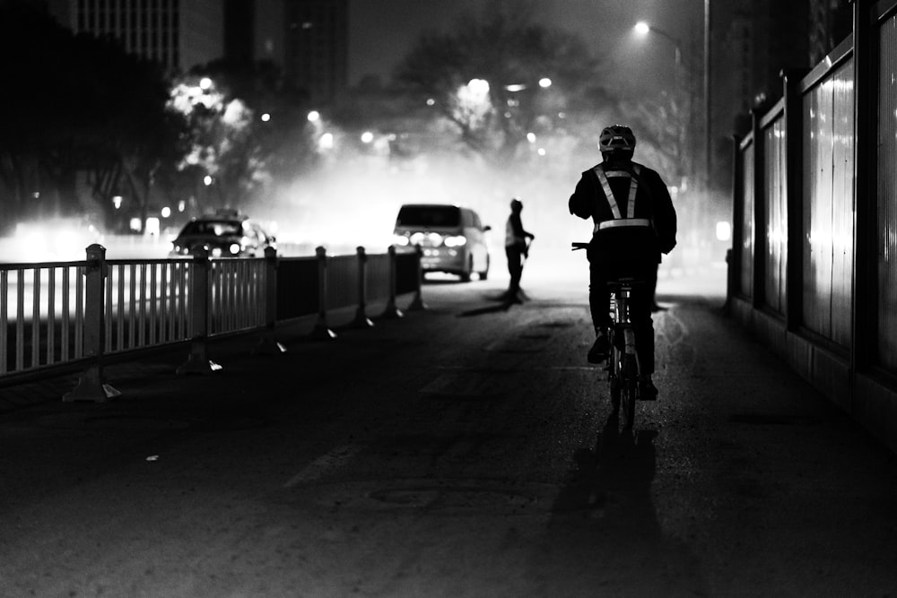 grayscale photo of man riding bike
