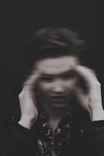 Patient holding head with dizziness, blurred background showing spinning effect