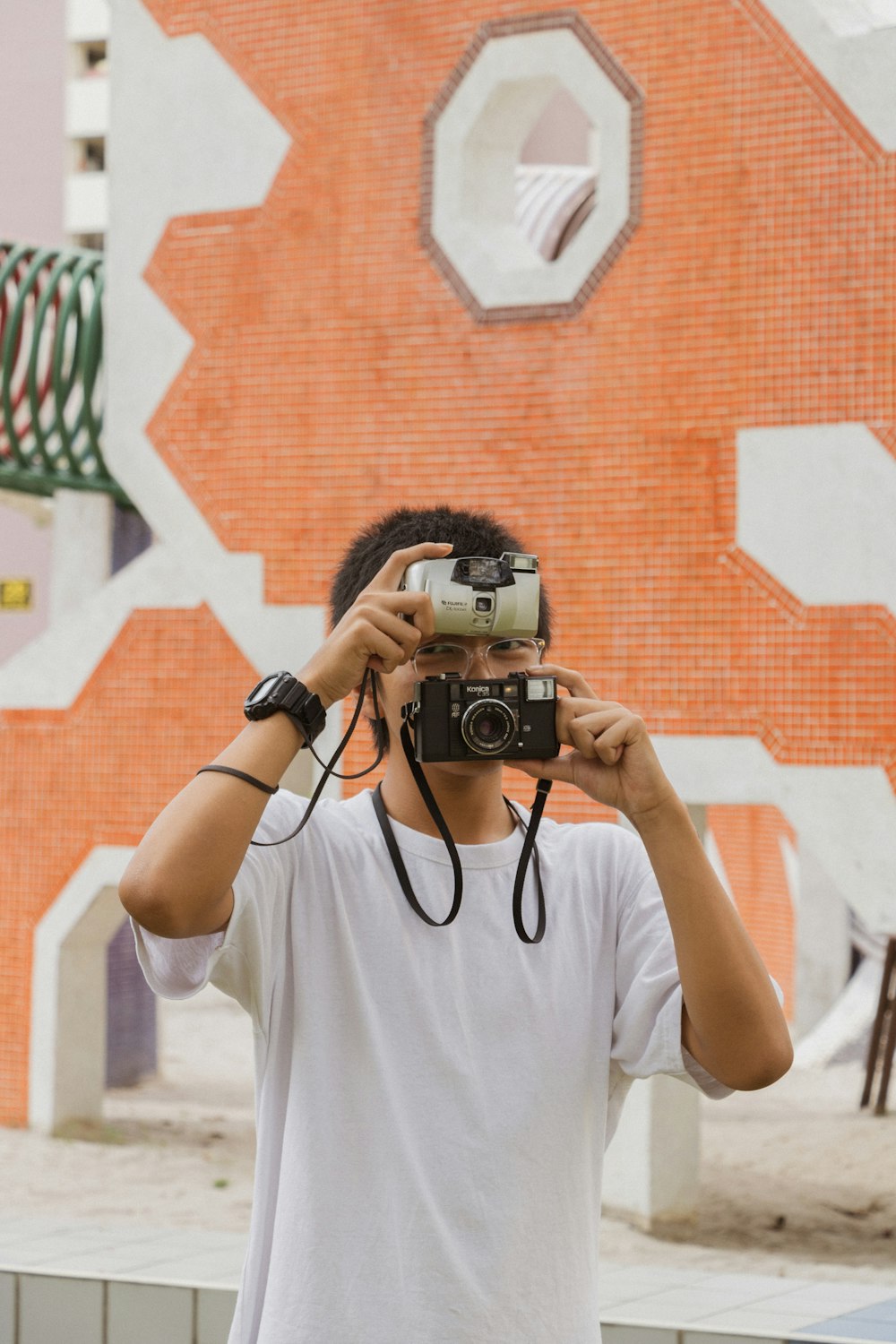 man covering his face with two cameras