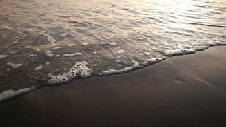 A slow-motion capture of waves gently folding on a sandy shore.