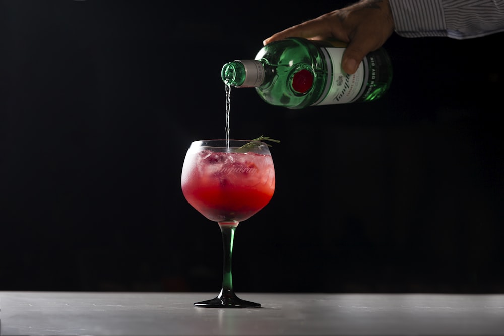 person pouring beverage on wine glass