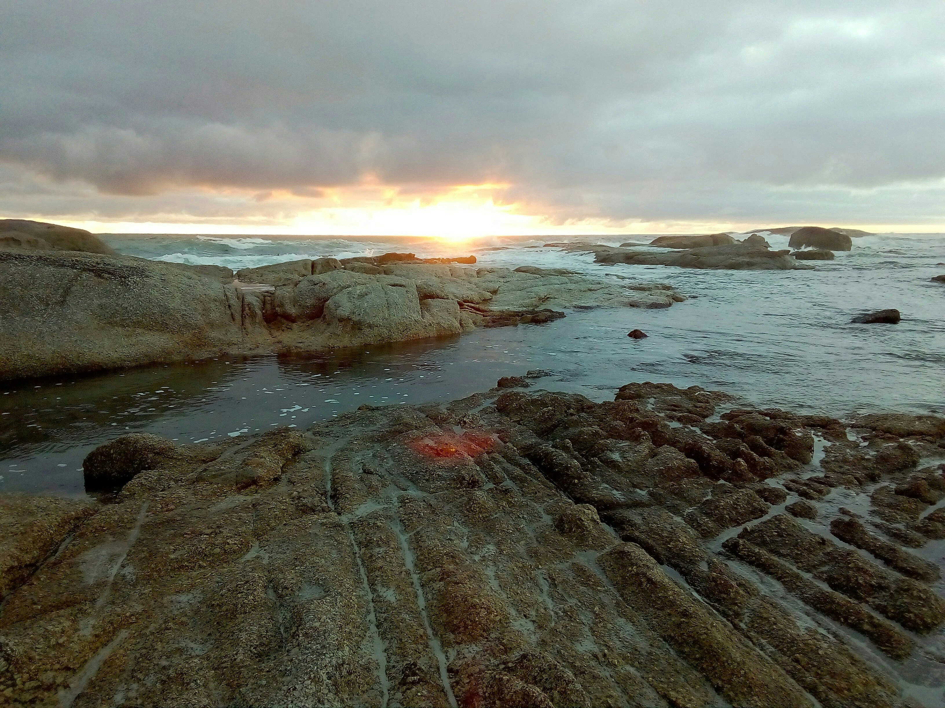 boulders in ocean under whcloudy sky