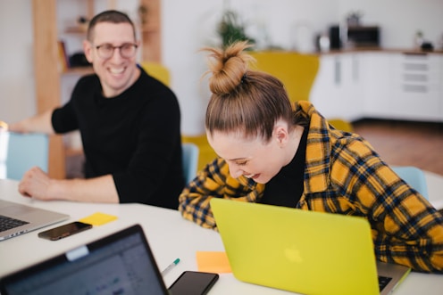 man and woman laughing while sitting in front of laptops onlyfans