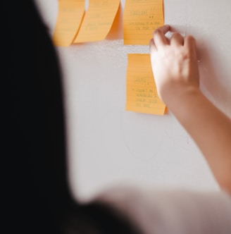 woman putting orange sticky notes on wall