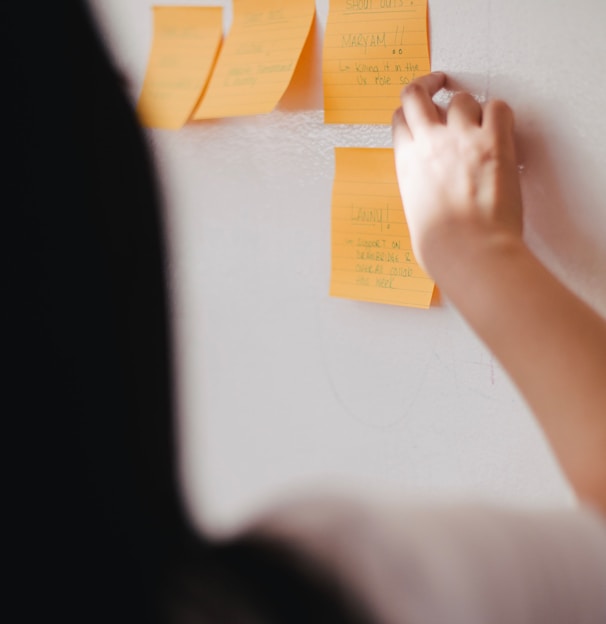 woman putting orange sticky notes on wall