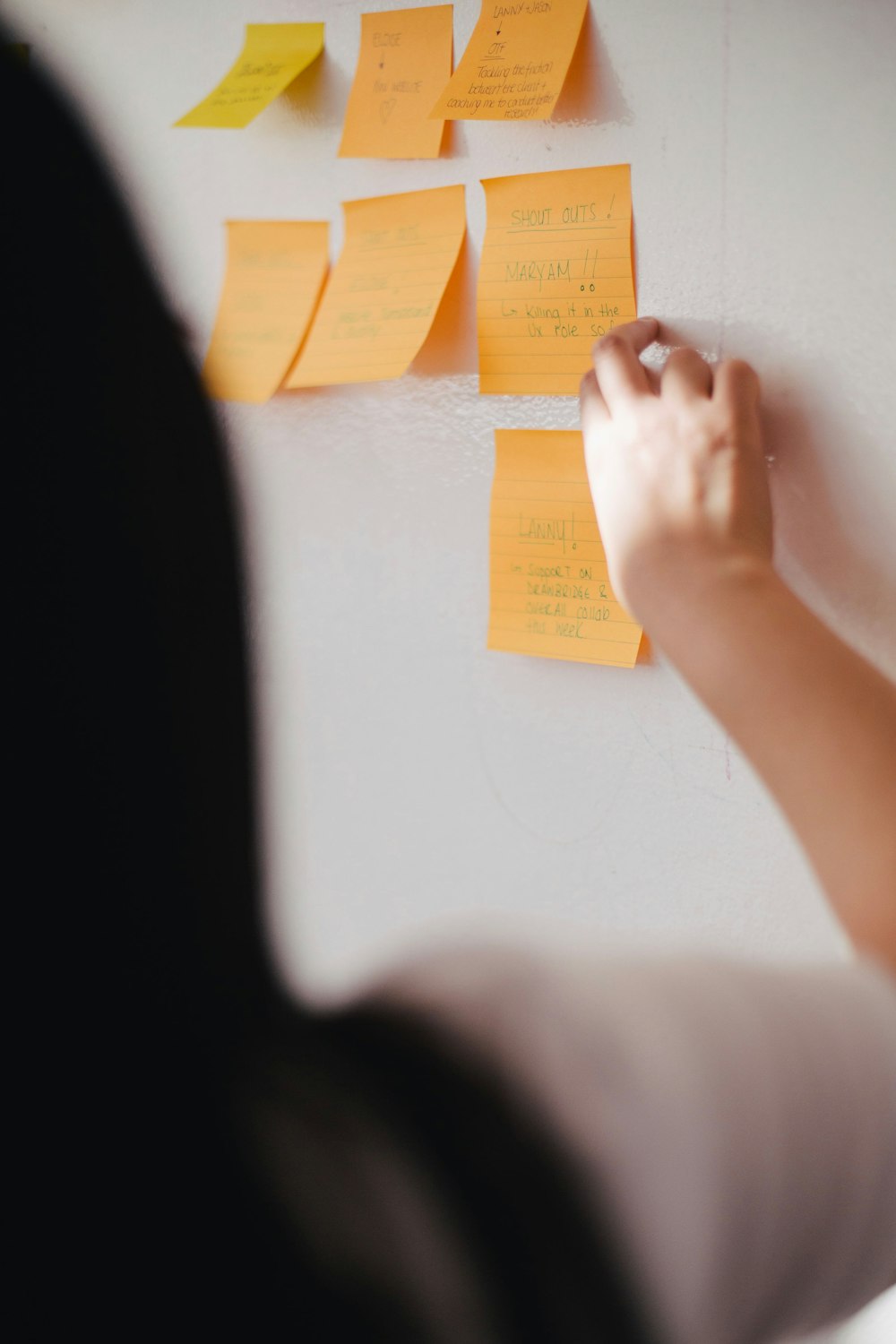 Frau legt orangefarbene Haftnotizen an die Wand