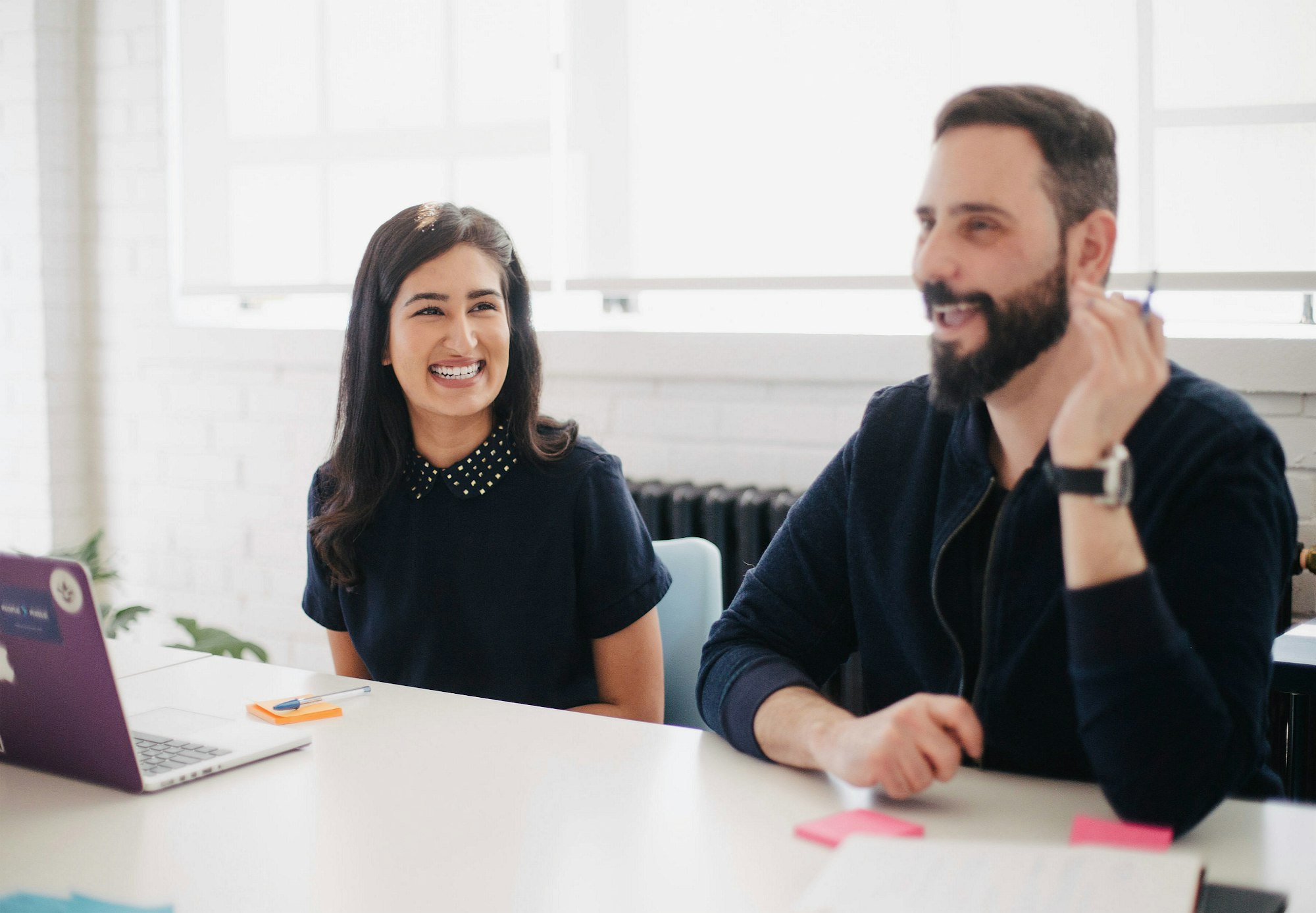 A woman and man sitting at a table in an office