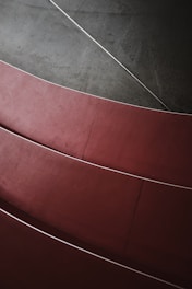 Curved red steps arranged in a pattern with a contrasting dark gray background, highlighting smooth lines and geometric shapes.