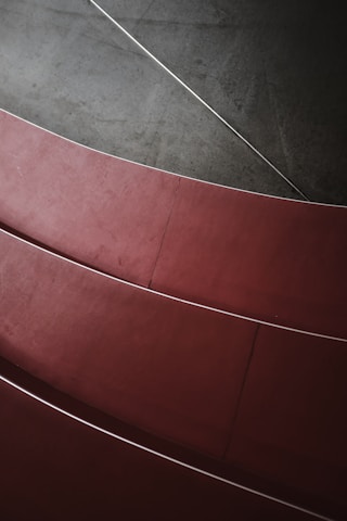 Curved red steps arranged in a pattern with a contrasting dark gray background, highlighting smooth lines and geometric shapes.