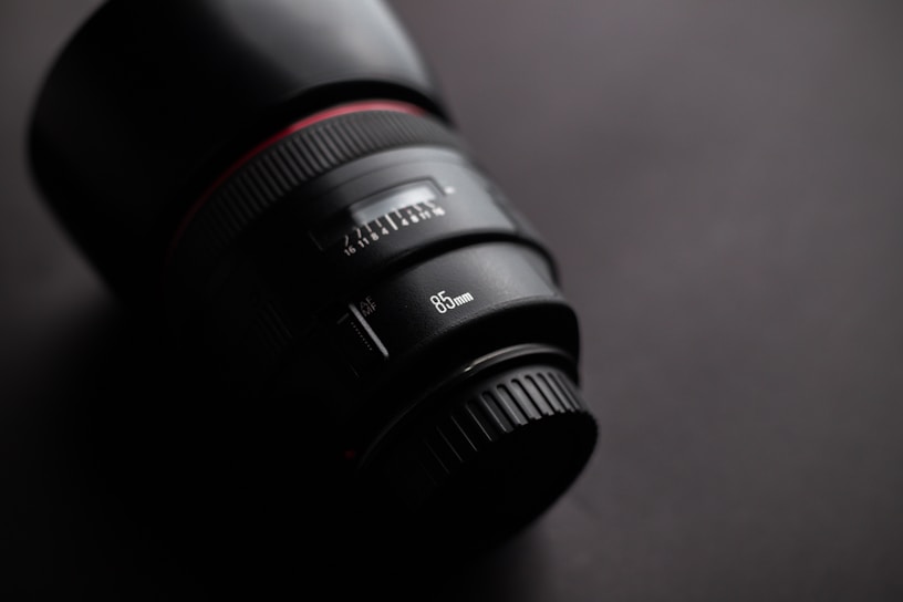 Close-up of a sleek black and gold luxury lens reflecting soft studio lighting.
