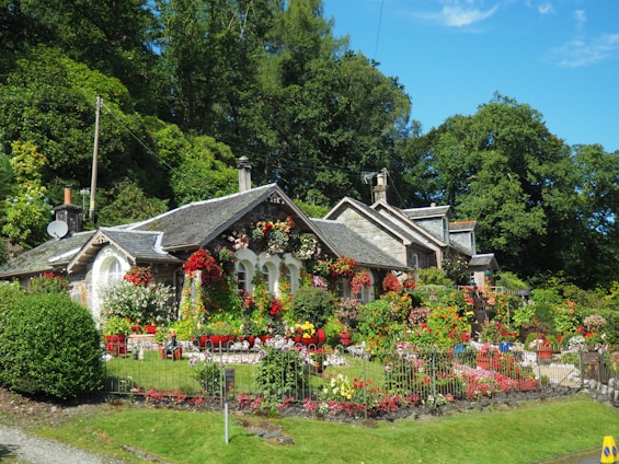 A charming cottage surrounded by beautiful gardens and trees.
