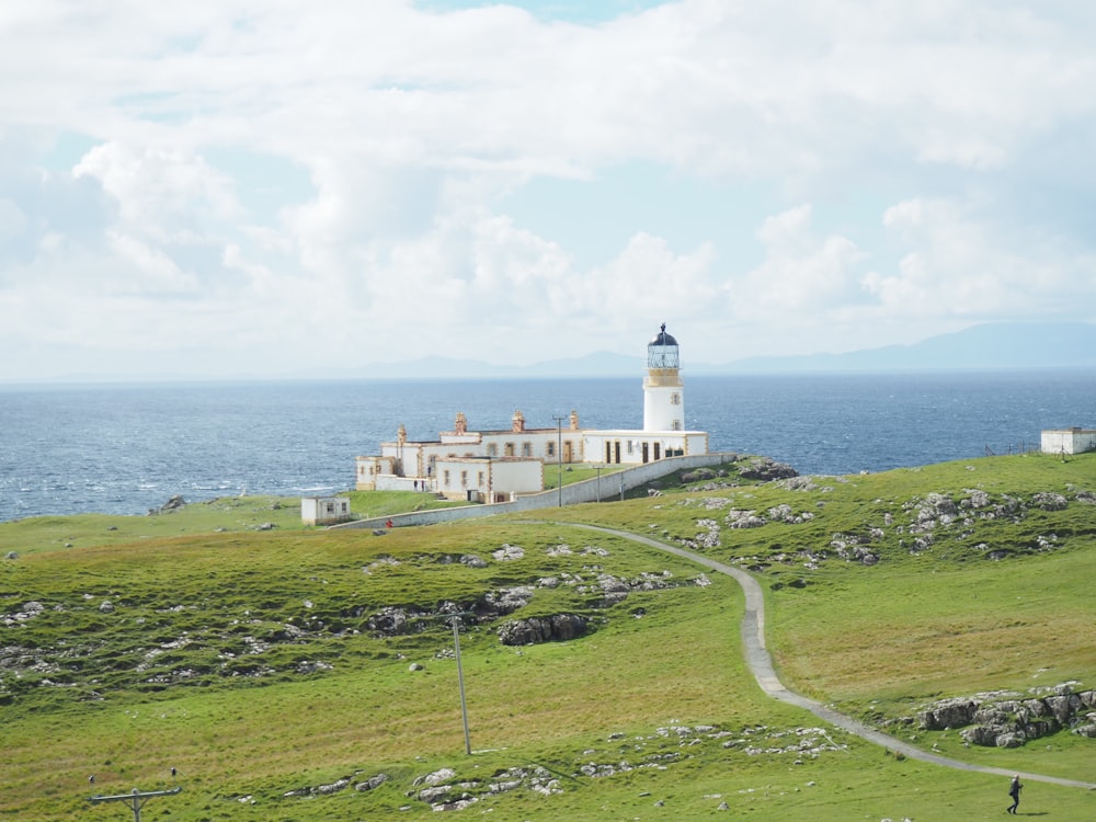 whit lighthouse facing ocean under white sy