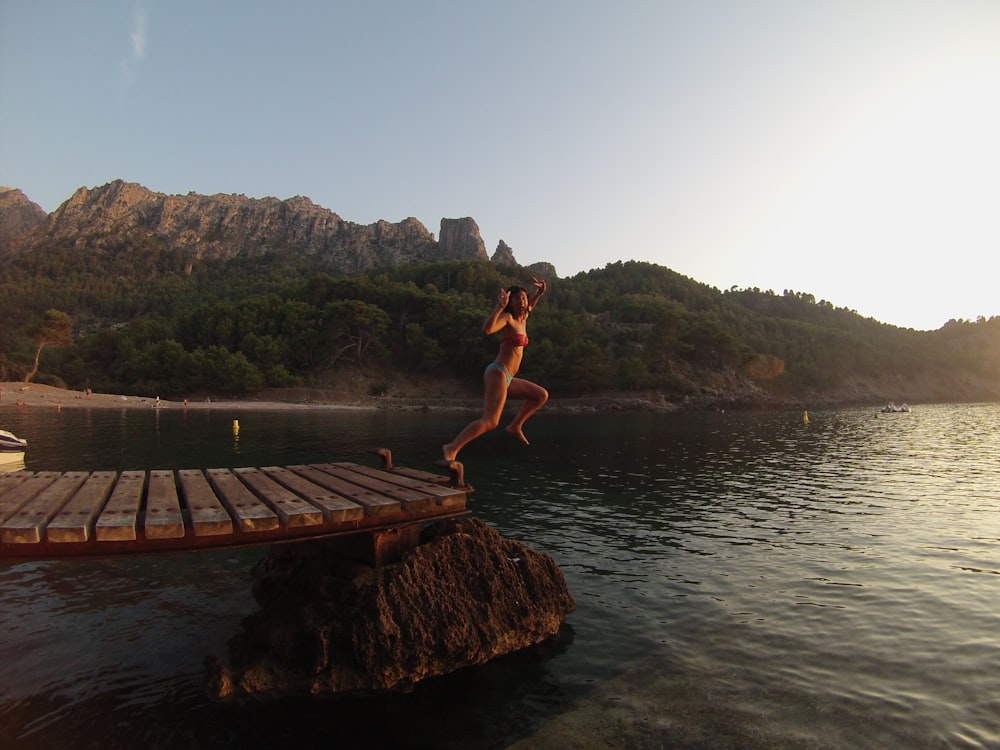 person jumping at the dock during daytime