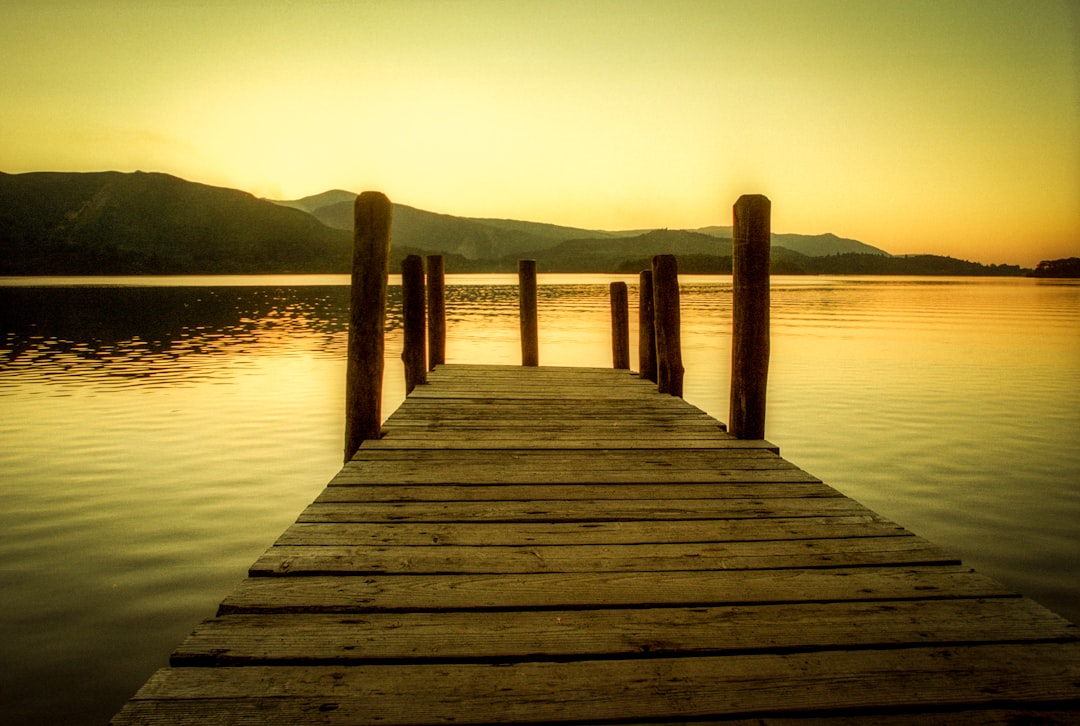 brown wooden dock at the lake during sunset