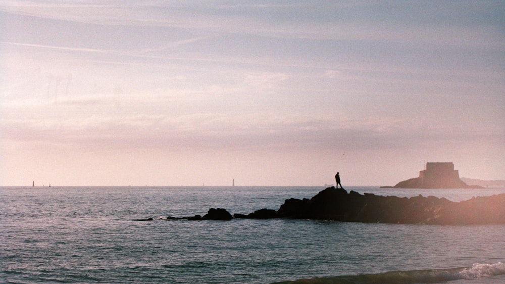 person standing on rock near ocean