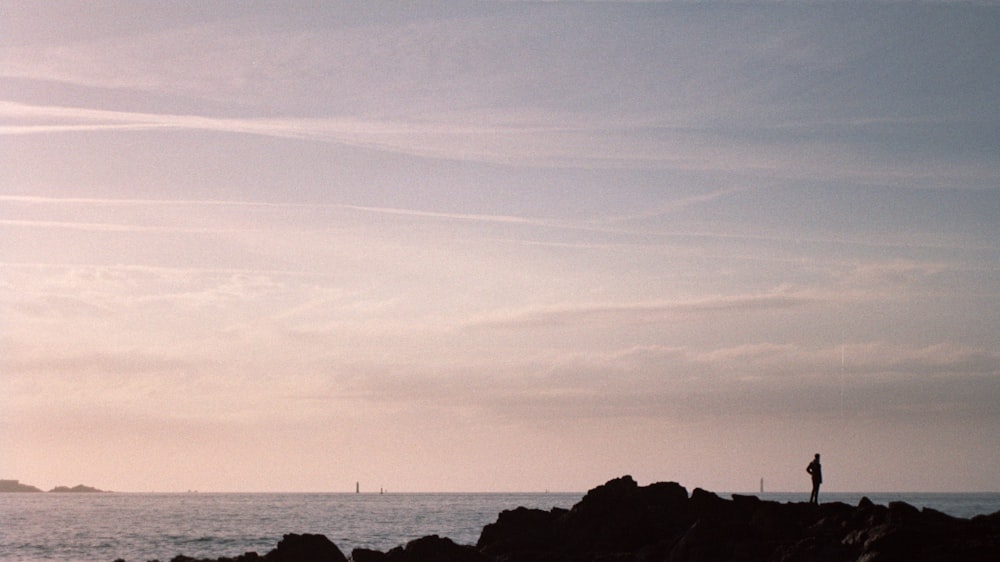 person standing on rock near ocean