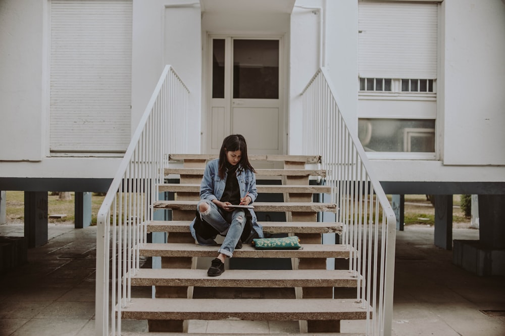 woman sitting on stair while holding book