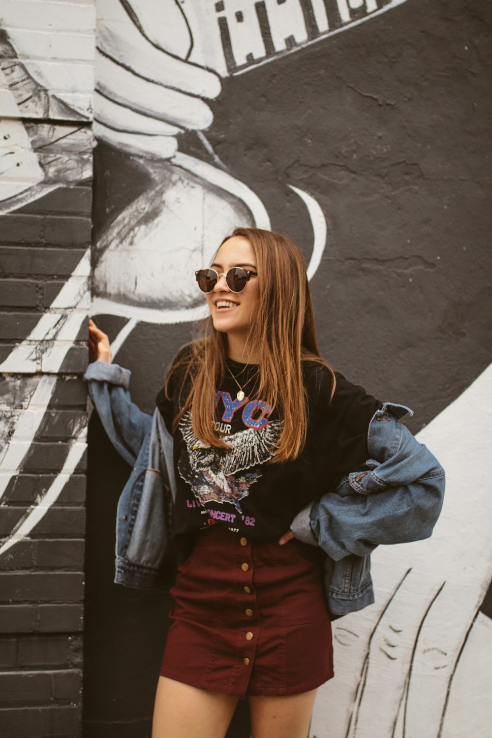 woman wearing blue denim jacket standing beside wall