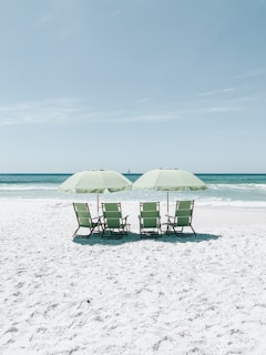cadeiras verdes sob guarda-sóis de frente para o mar azul
