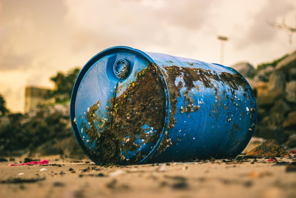 blue plastic barrel with mud on the ground